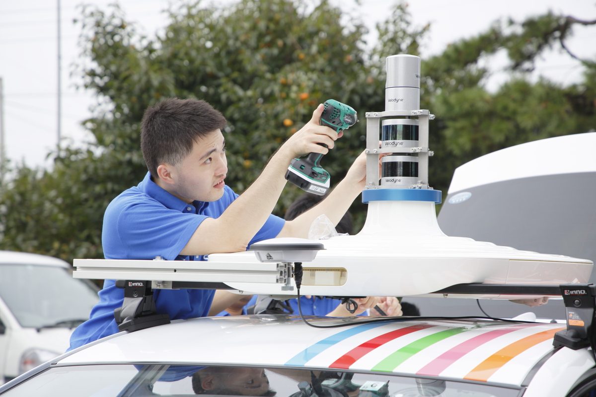 実験車の屋根にLiDARを取り付ける学生